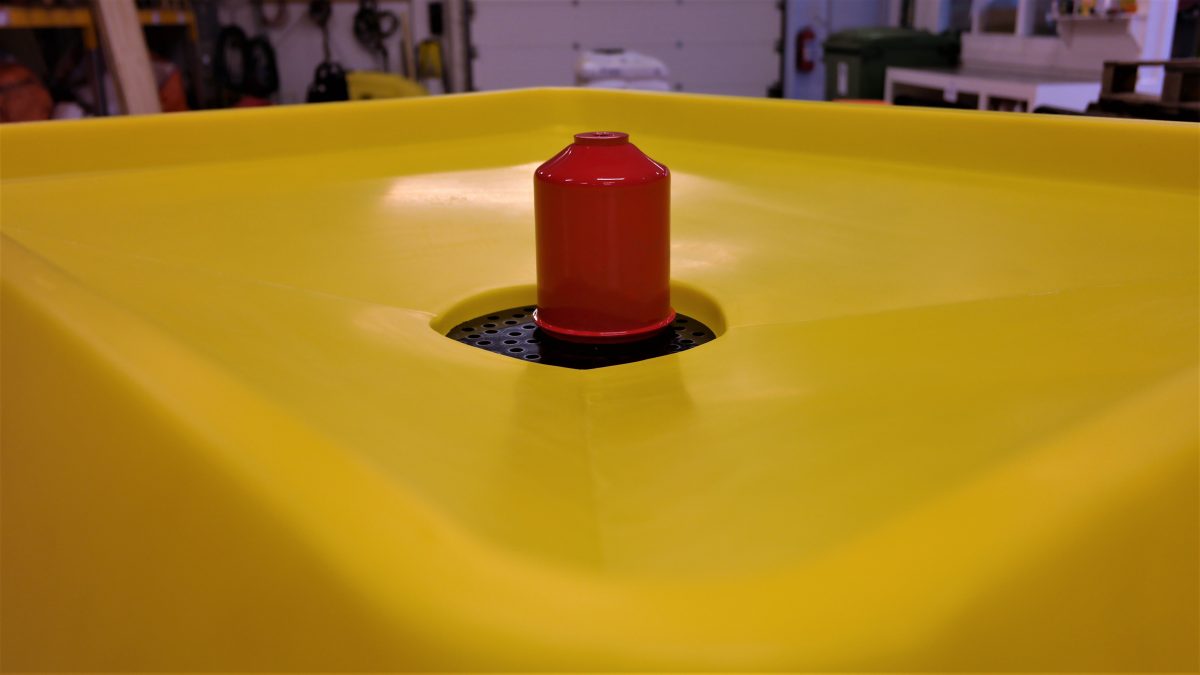 Rødt oljefilter står på sil i stor gul trakt. Foto